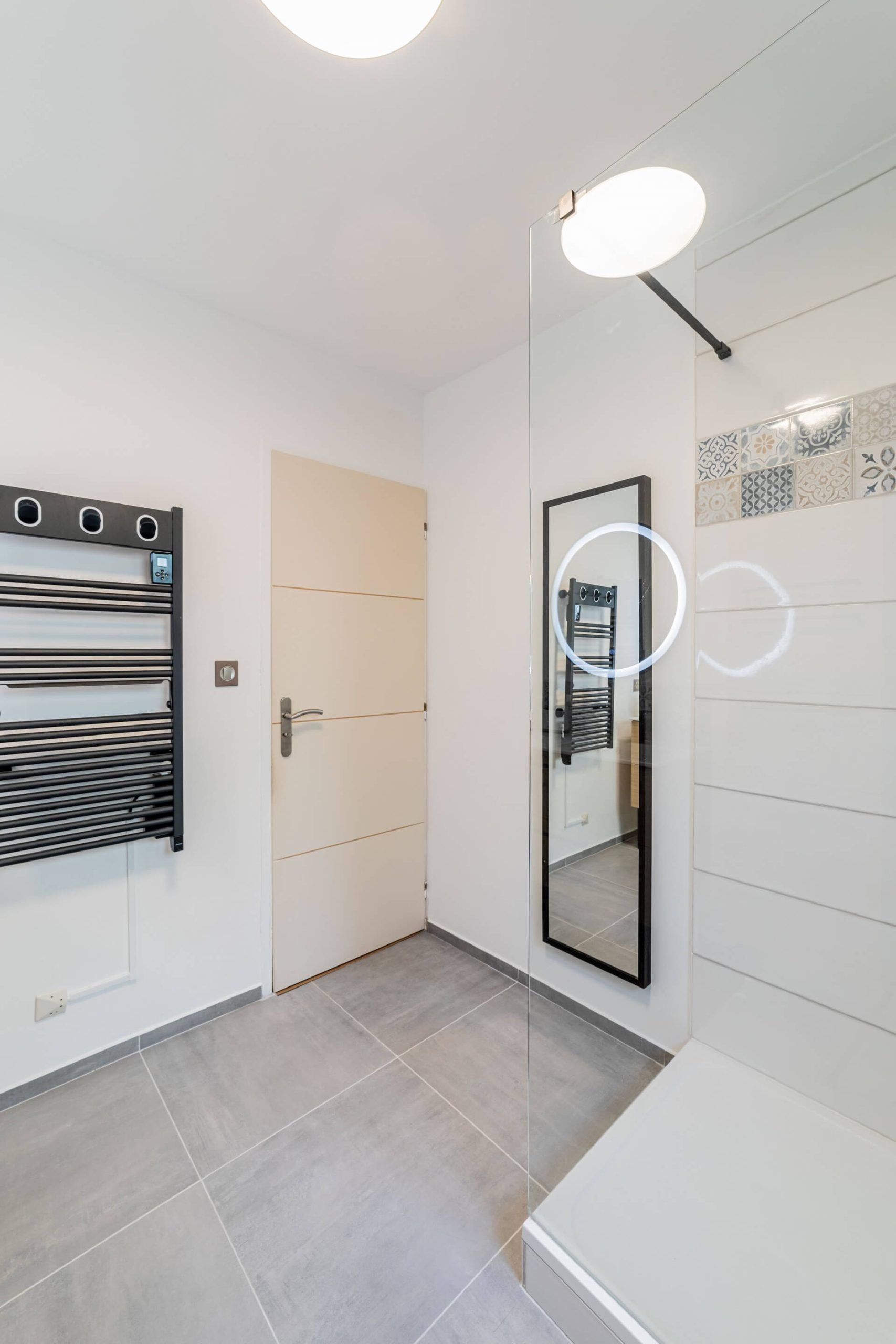 Carrelage grand format posé au sol d'une salle de bain rénovée, avec découpes autour du receveur de douche
