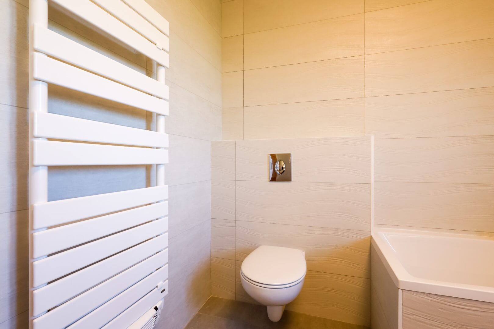 WC suspendu installé sur un coffrage plein, à côté d'un sèche-serviettes